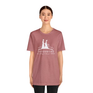 May include: A heather red t-shirt with a white graphic of a couple walking on a bridge. The graphic includes the text "Introverted but willing to discuss C-DRAMA".