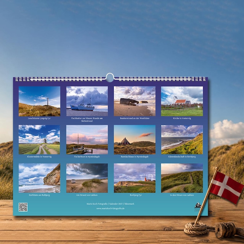 Op de afbeelding: Een wandkalender met twaalf landschapsfoto's van Denemarken, waaronder vuurtorens, kustgezichten en traditionele gebouwen. De kalender heeft een witte spiraalbinding aan de bovenkant en toont de tekst Martin Koch Fotografie Kalender 2023.