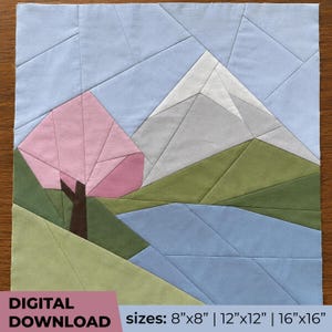 May include: A fabric quilt block pattern featuring a landscape with a pink cherry blossom tree, a snow-capped mountain in white and gray, green hills, and a blue sky. The text reads DIGITAL DOWNLOAD sizes: 8"x8" | 12"x12" | 16"x16".