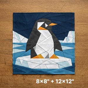 May include: A square fabric quilt block featuring a geometric pieced penguin design in black, white, and orange on a blue background with icebergs. The text 8x8" + 12x12" is printed at the bottom, indicating the available sizes for this pattern.