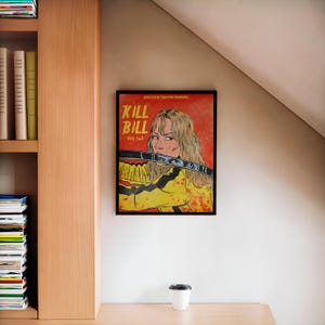 May include: A framed poster with a comic book style illustration of a woman holding a sword. The poster is red and yellow with the text "Kill Bill Vol. 1 & 2" and "Directed by Quentin Tarantino".