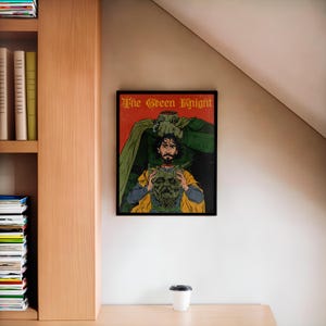 May include: A framed poster with the title "The Green Knight" in a vintage style font. The poster features a green knight holding the head of a man in his hand. The man is wearing a yellow and red robe.
