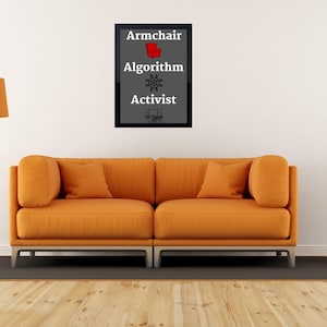 Könnte beinhalten: Ein gerahmter Druck mit den Worten "Armchair Algorithm Activist" in weißer Schrift auf grauem Hintergrund. Die Wörter sind vertikal übereinander angeordnet. Der Druck hängt an einer weißen Wand über einem leuchtend orangefarbenen Sofa.