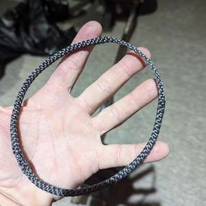 May include: A black and white braided rope ring.