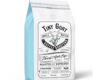 Puede incluir: Una bolsa blanca de granos de café con un borde azul. La bolsa presenta un logotipo de una cabra con el texto "Tiny Goat Small Batch Coffee Roasters". La bolsa también incluye el texto "Normal 3 Goats Ago Roasted Espresso" y "Fair Trade".