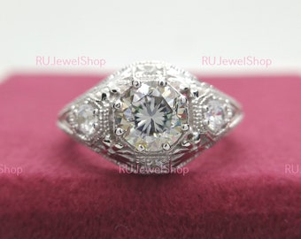 May include: A silver ring with a large, round, clear gemstone surrounded by smaller clear gemstones. The ring has an intricate, detailed design.