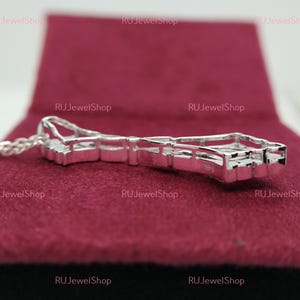 May include: A silver pendant necklace with a geometric design featuring multiple small clear stones. The pendant is on a silver chain.