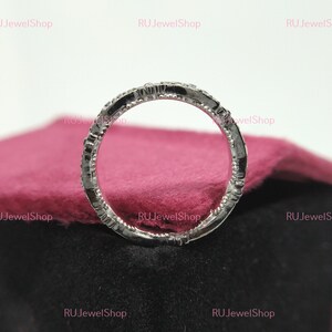 May include: A silver band ring with a row of small diamonds set in the band. The ring is on a pink velvet surface.