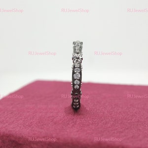 May include: A silver band ring with a row of small, clear cubic zirconia stones set in a delicate, curved design.