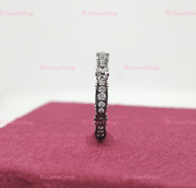 May include: A silver band ring with a row of small, clear cubic zirconia stones set in a delicate, curved design.