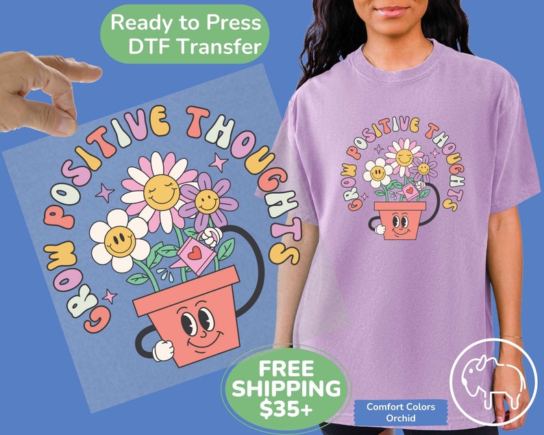 May include: A purple t-shirt with a graphic design of a flower pot with a smiling face and the text "Grow Positive Thoughts".
