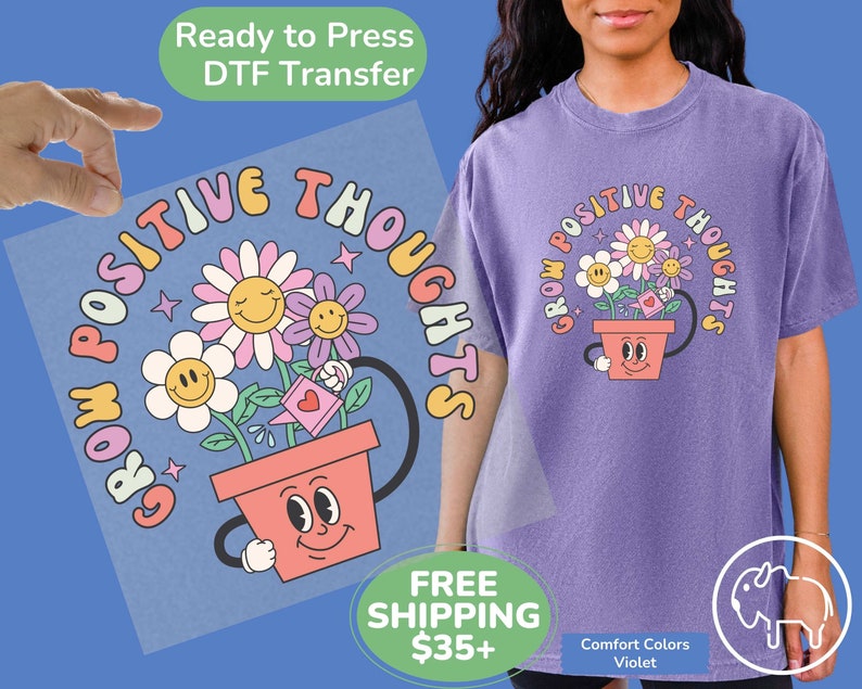 May include: A purple t-shirt with a graphic of a flower pot with smiling flowers and the text "Grow Positive Thoughts".