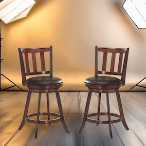 May include: Two brown wooden swivel bar stools with black faux leather seats. The stools are in a studio setting with white brick walls and a backdrop.