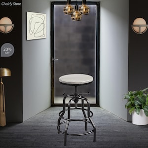 May include: A black metal swivel bar stool with a white wood top. The stool has a round seat and a footrest. The stool is in a room with a door and a light fixture.