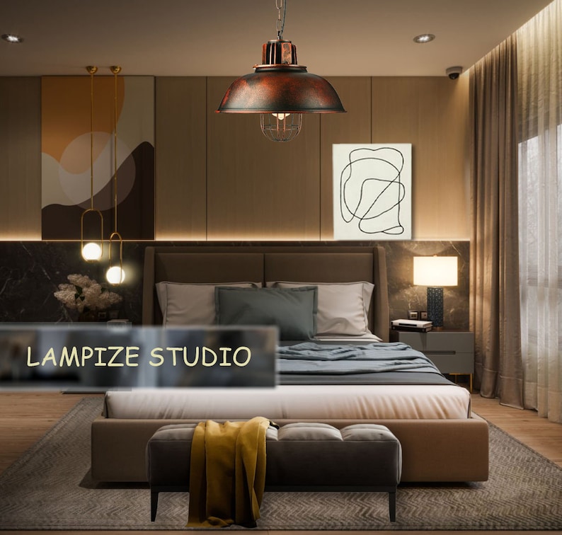 May include: A bedroom with a large bed, a brown leather headboard, and a brown leather footboard. The bed has a white duvet and a gray throw blanket. There is a brown leather ottoman in front of the bed with a yellow throw blanket on it. There is a large, rusty-colored pendant light hanging over the bed. The pendant light has a cage-like design. There is a white framed picture on the wall behind the bed. The picture has a black line drawing of a shape. There is a brown lamp on a nightstand next to the bed. The lamp has a white shade. There is a brown rug on the floor. The text "LAMPIZE STUDIO" is visible in the lower left corner of the image.