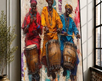 May include: A framed wall art print depicting three individuals wearing vibrant red, yellow, and blue traditional tunics and headwraps, each playing a wooden drum. The background features a textured, abstract paint splatter design in neutral tones.