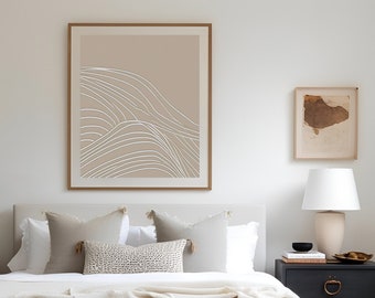 May include: A white bed with a white duvet and a brown woven bench at the foot of the bed. There are white pillows and a brown and white patterned pillow on the bed. A black nightstand with two drawers is on the right side of the bed. A white lamp with a white shade is on the nightstand. There is a framed print of abstract lines on the wall above the bed.