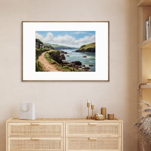 Könnte beinhalten: Ein gerahmtes Foto einer Küstenlandschaft mit einem Feldweg, der zu einem kleinen Haus auf einer Klippe führt, die auf das Meer blickt. Das Wasser ist blau und grün, und im Vordergrund befinden sich Felsen und Wellen.