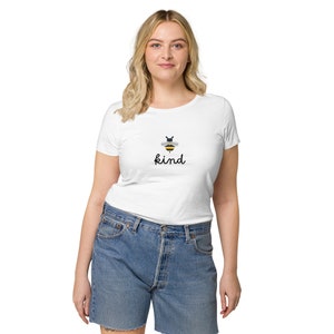 Op de afbeelding: Wit T-shirt met een zwart en geel bijenmotief en het woord "kind" in zwarte cursieve letters.