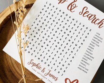Könnte beinhalten: Eine weiße Karte mit einem Sip & Search Wortspiel in rostfarbenem Text. Die Karte enthält die Namen Sophie & James, das Datum 23. September 2024 und eine Liste von Wörtern zum Thema Hochzeit. Ein getrockneter Blumenstiel ist mit Schnur befestigt.