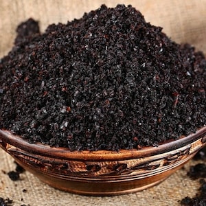 May include: A wooden bowl filled with dark brown Turkish black cumin seeds, also known as black caraway seeds. The seeds are used as a spice and are often used in Middle Eastern and Mediterranean cuisine.