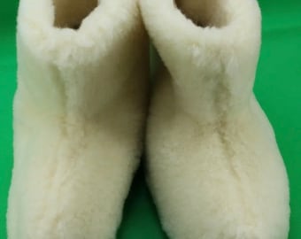 May include: A pair of white sheepskin slippers. The slippers are made of soft, fluffy sheepskin and have a closed toe.