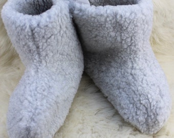 May include: A pair of gray fuzzy slipper boots. The boots are made of a soft, plush material and have a closed toe design.