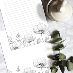 Może przedstawiać: Dwa arkusze papieru listowego w linie z czarno-białym rysunkiem maków i liści u dołu każdego arkusza.