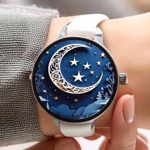 Peut inclure: Montre-bracelet argentée avec un bracelet blanc. Le cadran de la montre présente un motif bleu avec un croissant de lune et des étoiles. La montre a un cadran rond et une lunette argentée.