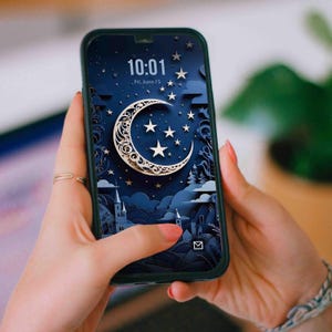 May include: Smartphone displaying a dark blue wallpaper with a crescent moon, stars, and a castle silhouette. The time 10:01 and the date Fri, June 15 are visible on the screen. The phone is held in a black case.