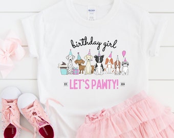 May include: White t-shirt with a pink birthday girl graphic featuring a line of dogs wearing party hats. The text reads "birthday girl" and "Let's Pawty!" with the years "EST. 2024".
