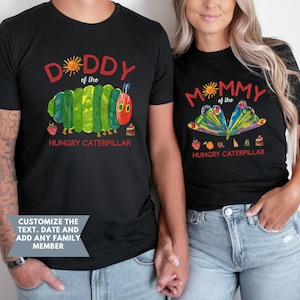Może przedstawiać: Czarne koszulki z kolorowymi ilustracjami i tekstem. Jedna koszulka m&oacute;wi "DADDY of the HUNGRY CATERPILLAR" z projektem gąsienicy. Druga m&oacute;wi "MOMMY of the HUNGRY CATERPILLAR" z projektem motyla. Obie koszulki mają dodatkową grafikę.