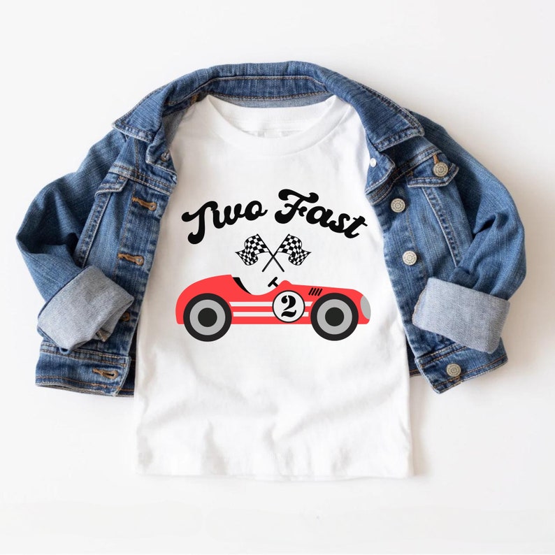 May include: White t-shirt with a red race car and the text "Two Fast" in black. Two checkered flags are crossed above the car.