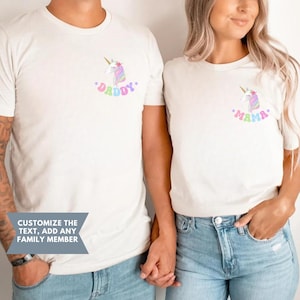 Puede incluir: Dos camisetas blancas con gr&aacute;ficos de unicornios. Una camiseta tiene la palabra "Daddy" y la otra "Mama", ambas en colores pastel. Las camisetas las llevan dos personas y el texto "Personaliza el texto, a&ntilde;ade cualquier miembro de la familia" es visible.