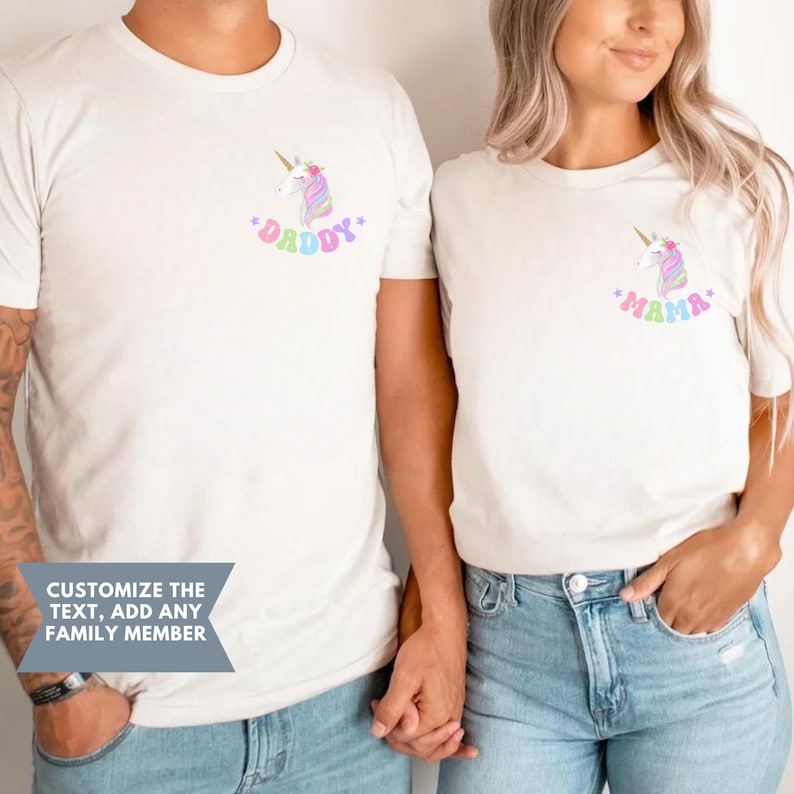 Puede incluir: Dos camisetas blancas con gr&aacute;ficos de unicornios. Una camiseta tiene la palabra "Daddy" y la otra "Mama", ambas en colores pastel. Las camisetas las llevan dos personas y el texto "Personaliza el texto, a&ntilde;ade cualquier miembro de la familia" es visible.