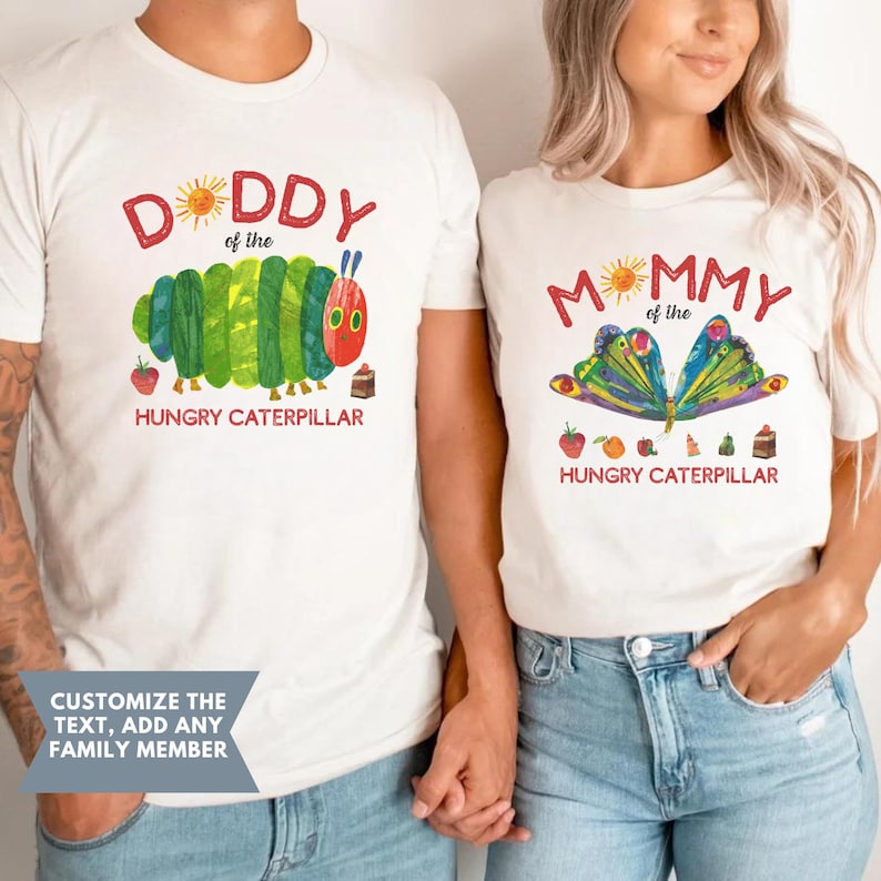 Może przedstawiać: Dwie pasujące białe koszulki z ilustracjami z "Bardzo głodnej gąsienicy". Jedna z napisem "DADDY" i gąsienicą, druga z "MOMMY" i motylem. Pod każdym obrazkiem napis "HUNGRY CATERPILLAR".