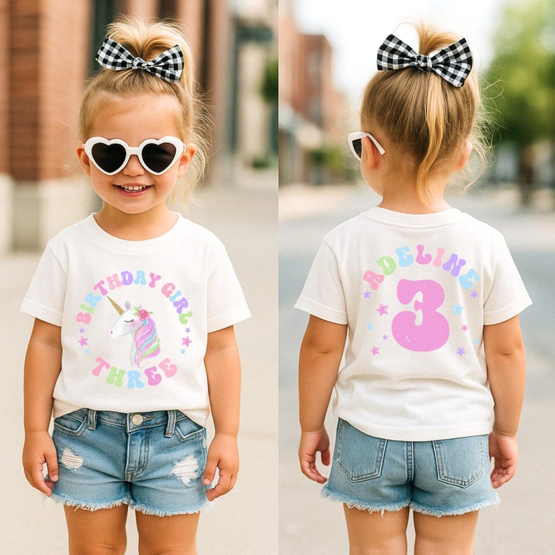 Puede incluir: Una ni&ntilde;a lleva una camiseta blanca con un dise&ntilde;o de unicornio y el texto "BIRTHDAY GIRL THREE". La parte trasera de la camiseta muestra el nombre "ADELINE" y el n&uacute;mero "3". La ni&ntilde;a tambi&eacute;n lleva pantalones cortos vaqueros, gafas de sol en forma de coraz&oacute;n y un lazo blanco y negro.