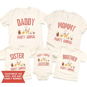 Peut inclure: Ensemble de t-shirts et un body cr&egrave;me pour la famille, avec du texte rouge et un th&egrave;me d'animaux de f&ecirc;te. Les t-shirts indiquent "Daddy", "Mommy", "Sister" et "Brother", avec un body pour "Jackson". Chaque v&ecirc;tement a un motif animalier color&eacute;.