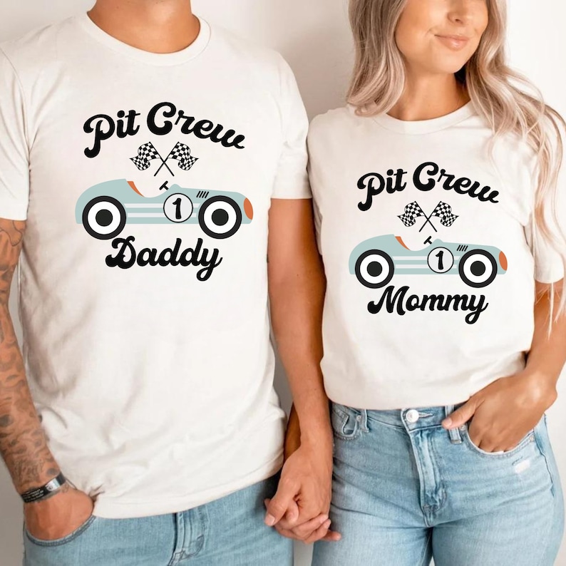 May include: Two white t-shirts with a blue race car graphic and the text "Pit Crew Daddy" and "Pit Crew Mommy".