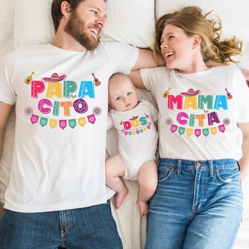 Peut inclure: Une famille de trois personnes portant des t-shirts blancs assortis avec du texte et des motifs color&eacute;s. Les t-shirts disent "Papa Cito", "Mama Cita" et "Dos".