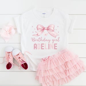Puede incluir: Camiseta blanca con un lazo rosa y el texto "Birthday girl ADELINE".