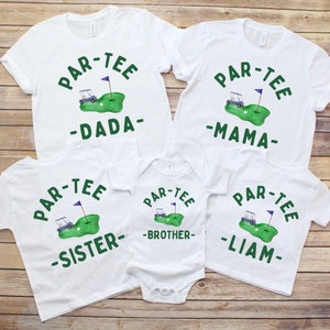 May include: White t-shirts and a onesie with a golf-themed design. Each shirt features the words "PAR-TEE" above a golf course graphic and a name below: DADA, MAMA, SISTER, BROTHER, and LIAM. The design includes a golf cart, flag, and golf ball.