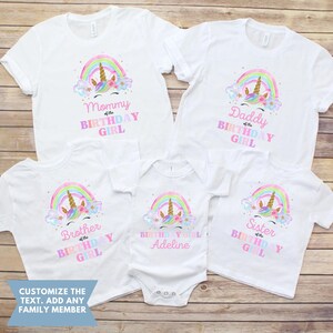 K&ouml;nnte beinhalten: Satz von f&uuml;nf wei&szlig;en T-Shirts mit einem Einhorn- und Regenbogen-Design. Die Shirts zeigen die Aufschriften "Mami des Geburtstagsm&auml;dchens", "Papa des Geburtstagsm&auml;dchens", "Bruder des Geburtstagsm&auml;dchens", "Geburtstagsm&auml;dchen Adeline" und "Schwester des Geburtstagsm&auml;dchens".