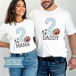May include: Two white t-shirts with a blue number two, a soccer ball, a football, and the words "Mama" and "Daddy".