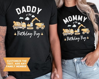 Peut inclure: T-shirts noirs avec des motifs assortis. L'un dit "DADDY of the Birthday Boy" et l'autre "MOMMY of the Birthday Boy". Les deux t-shirts présentent des véhicules de chantier jaunes et oranges.