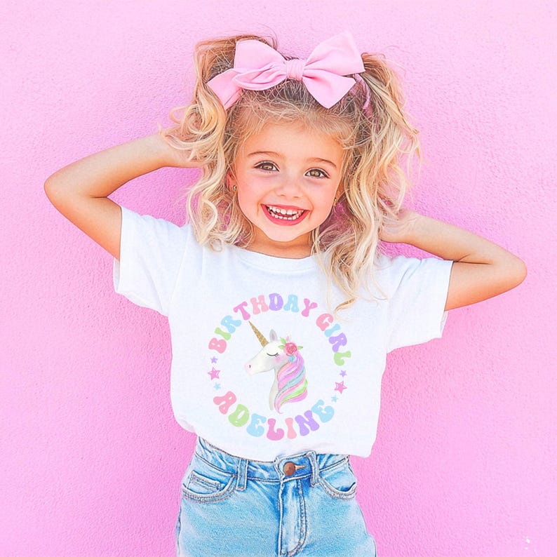 May include: A white t-shirt with a rainbow unicorn graphic and the text "Birthday Girl Adeline".