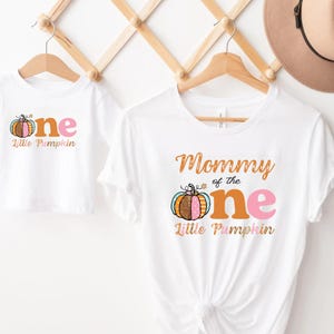 Puede incluir: Dos camisetas blancas con un dise&ntilde;o de calabaza y el texto "Mommy of the one Little Pumpkin" y "one Little Pumpkin".
