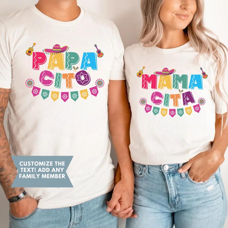 Peut inclure: Deux t-shirts blancs avec du texte et des graphismes color&eacute;s. Le texte sur le t-shirt de gauche dit "Papa Cito" et le texte sur le t-shirt de droite dit "Mama Cita".