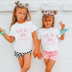 Puede incluir: Dos chicas con camisetas blancas con el texto "Hermana de la cumplea&ntilde;era" y un lazo rosa. La chica de la izquierda lleva pantalones cortos a cuadros blanco y negro y la chica de la derecha lleva pantalones cortos a cuadros rosa y blanco.