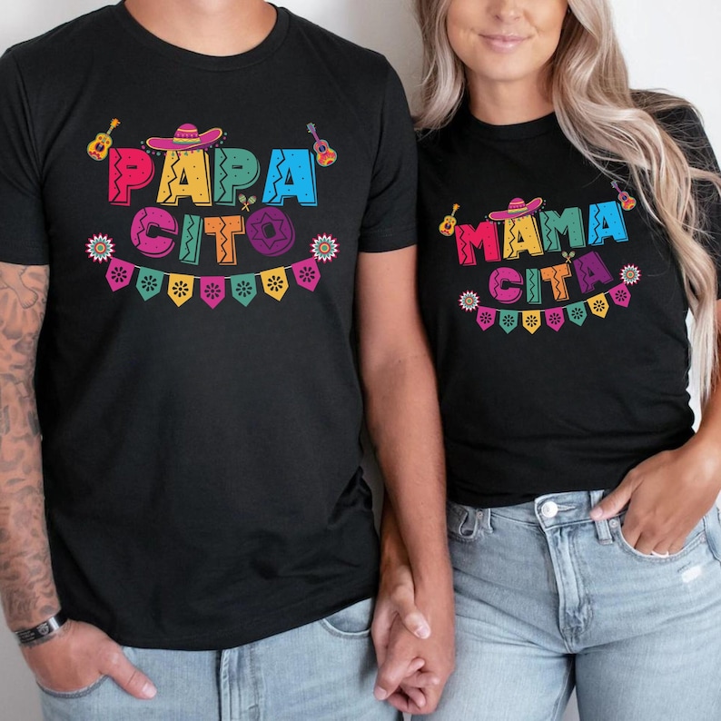 K&ouml;nnte beinhalten: Ein Paar tr&auml;gt passende schwarze T-Shirts mit buntem Text, der "Papa Cito" und "Mama Cita" sagt, mit einem festlichen mexikanischen Design.